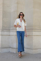 a lady in a white top, a white outerwear with hollow prints and a pair of jeans